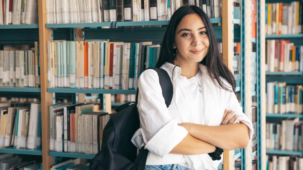 Young woman standing in front of library books